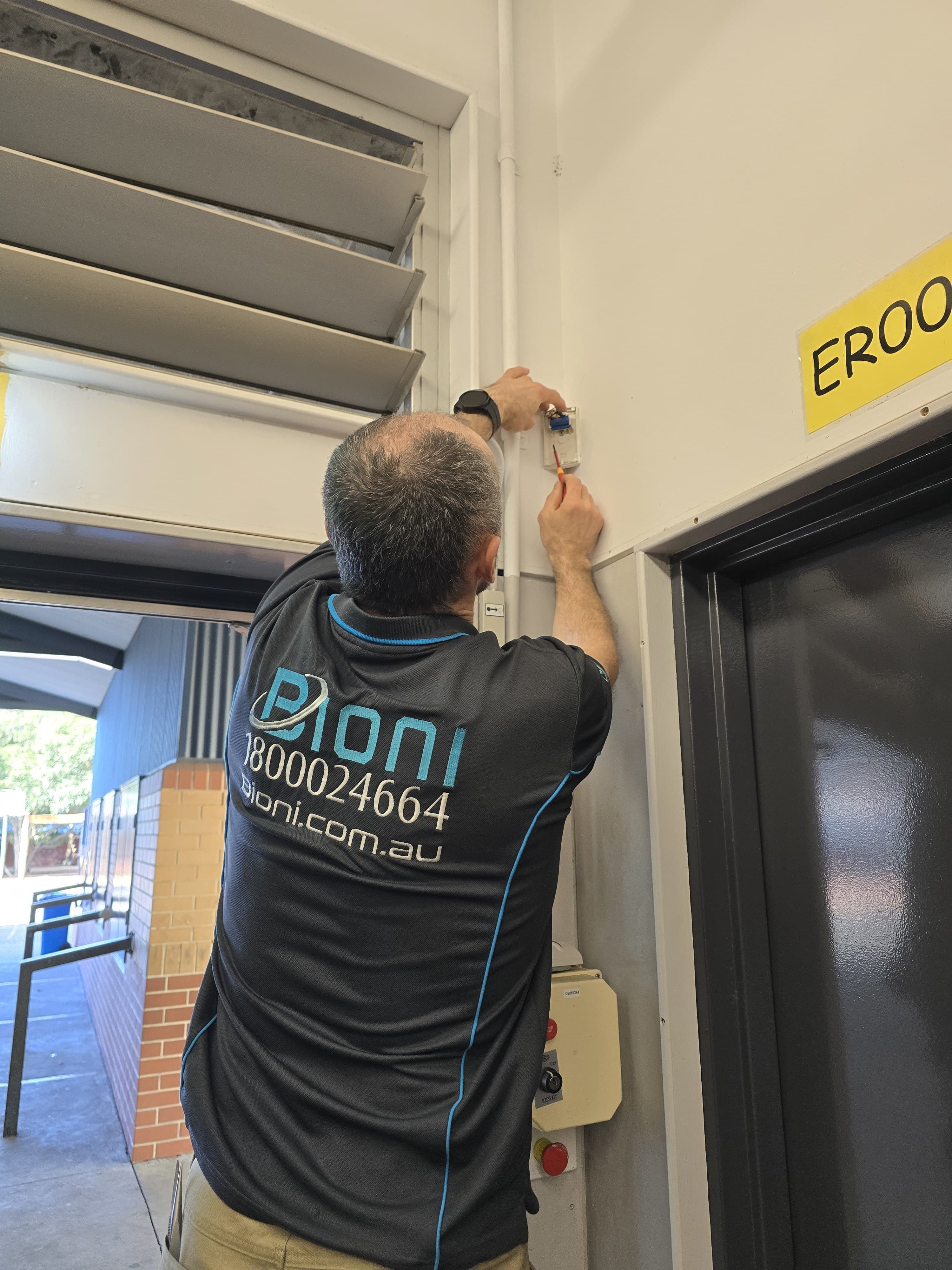 A Bioni technician installing a device above a doorway